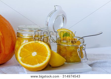 Pumpkin Jam Or Marmalade With Orange And Lemon. In The Background Is A Pumpkin. Two Glass Jars Of Pu