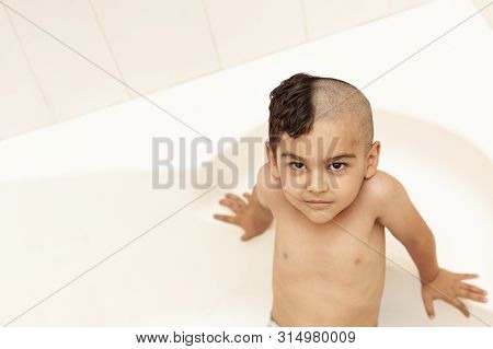 Six-year Boy At Haircutting At Home. Father Cut Half Of The Son's Hair Off At The Bathroom