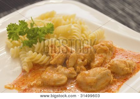 Hähnchenstücke mit Nudeln In Paprika-Sahne-Sauce. Horizontal.