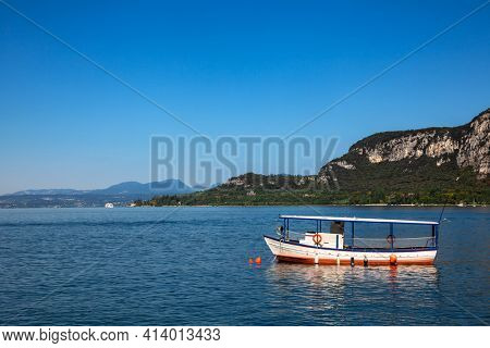 Pleasure boat moored near resort town on the eastern shore of Lake Garda in Northern Italy. Lake Garda is the largest lake in Italy and a popular holiday location on the edge of the Dolomites