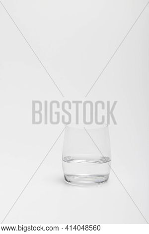 The Half Full Glass Of Pure Water Isolated On A White Background. A Drinking Glass Half Filled With 