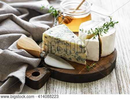 Various Types Of Cheese,  Blue Cheese,  Bree, Camambert And Honey On A Wooden Table