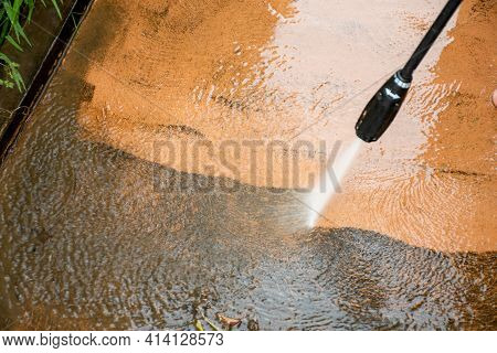 Selective Focus. Cleaning Backyard Paving Tiles With High Pressure Washer. Spring Clean Up