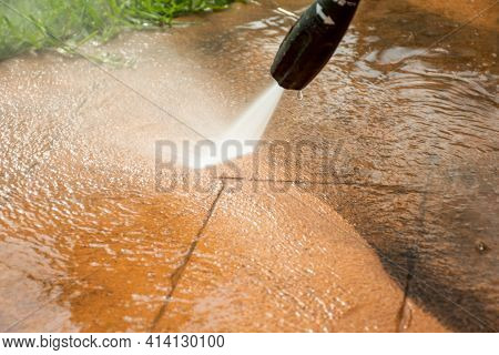 Selective Focus. Cleaning Backyard Paving Tiles With High Pressure Washer. Spring Clean Up