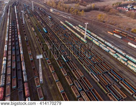 Drone shot over a railway sorting station with trains at sunset. Photo railway tracks with wagons, top view. Aerial top view.