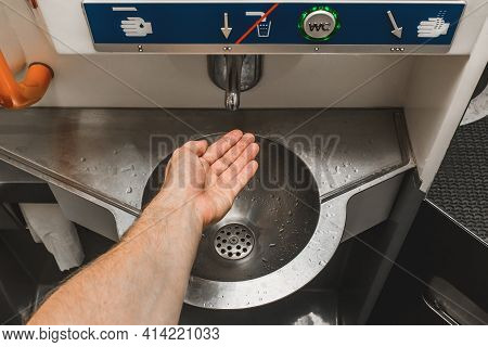 The Guy Brings His Hand To The Automatic Water Supply Tap In The Modern Toilet Of The Stadler Electr