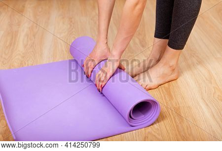 Equipment For Fitness, Pilates Or Yoga, Exercise Mat. Close Up Of A Womans Hands Is Rolling Up Exerc