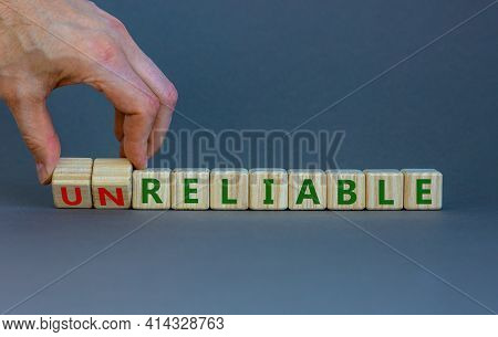 Unreliable Or Reliable Symbol. Businessman Turns Wooden Cubes And Changes The Word Unreliable To Rel