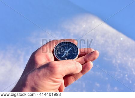 Compass In Hand On Snow Background. Orientation On Terrain In Forest And Mountain In Winter Time. Ma