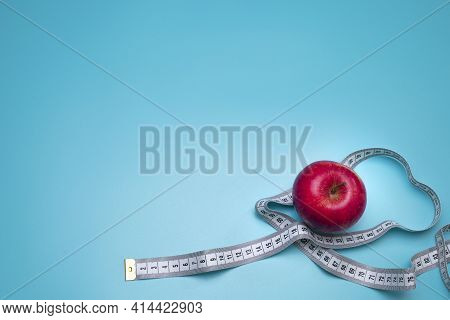 Tomato And Measuring Tape On The Blue Background. The Concept Of Diet. Free Space For Text.