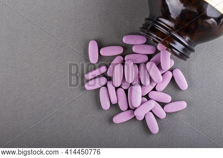 Lilac Medical Pills Are Falling Out Of A Bottle On A Gray Background. Concept Of Health, Drug Addict
