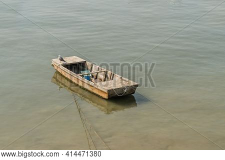 Seagull On Small Wooden Boat Floating In Ocean Port.