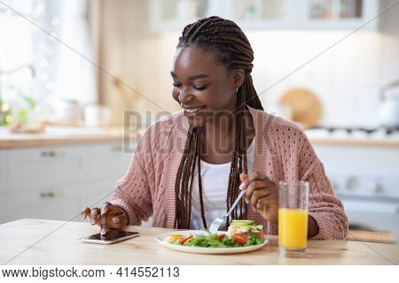 Callories Counting App. Black Woman Using Smartphone While Having Breakfast In Kitchen