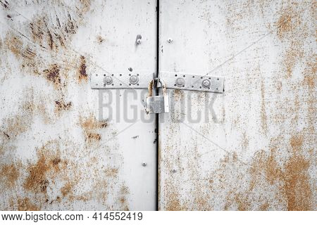 Metal Door With Lock Texture Background. White, Rusty Garage Gate. Old Worn Iron Plate With Peeled O