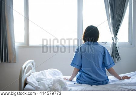 Back View Of Patient Woman Sitting On Bed In Hospital Ward, Looking Away At Window And Hope Everythi