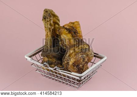 Shopping Basket With Dog Treats On A Pink Background. Chewy Treats In Metal Basket. Dried Beef Ears 