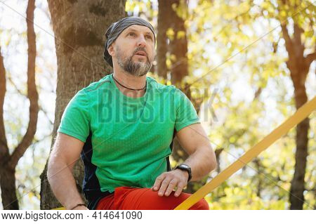 Portrait Of An Adult Man With A Beard In The Autumn Forest. Sportsman Slackline Next To A Taut Slack