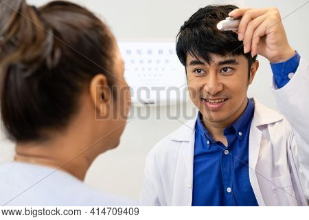 Selective Focus At Optometrist Face. While Doctor Using Penlight And Subjective Refraction To  Exami