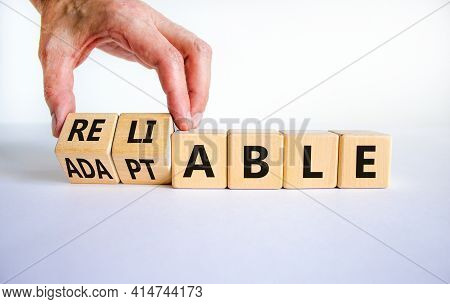 Adaptable Or Reliable Symbol. Businessman Turns Wooden Cubes And Changes The Word Adaptable To Relia