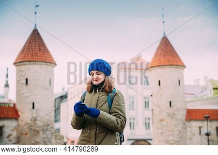 Tallinn, Estonia. Young Caucasian Confident Woman Backpacker Tourist Using Smartphone Near Landmark 