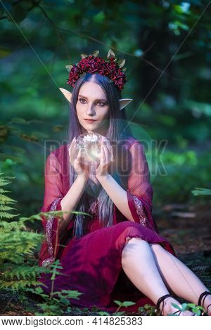 Caucasian Girl With Artistic Elf Ears And Flowery Garland Holding Glass Dome With Grounded Flower Wh