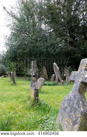 Castle Combe, Chippenham, Wiltshire, Uk - March 06, 2021: View Of An Old Graves With Green Grass In 