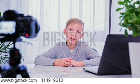 Child blogger videotapes his vlog at home. Boy recording his video blog. White boy speaks in front of a video camera for his blog channel. Little 8 year vlogger makes online streaming using smartphone