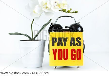 Pay As You Go Payg . Business Concept. Text On Yellow Sticker Prekpelen Alarm Clock Near Green Orchi