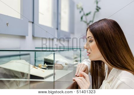 Close up view of girl looking at jewelry in window case at jeweler's shop. Concept of wealth and luxurious life