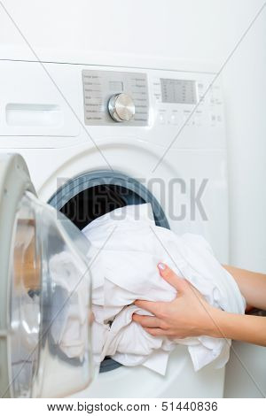 Young woman or housekeeper has a laundry day at home, she takes the laundry or whites out of your washing machine or the dryer