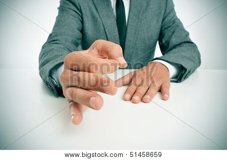 man wearing a suit sitting in a table gesturing as affirming his speech