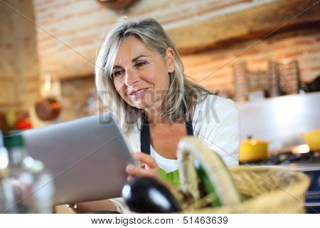 Senior woman cooking with help of recipe on tablet