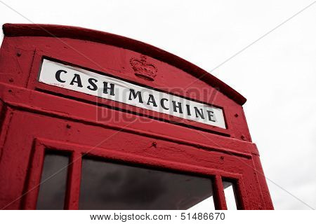 Iconic British red telephone booth converted to a cash machine with the sign above the door below the Royal crown
