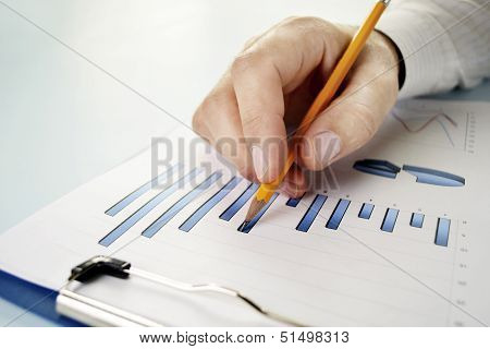 Man Holding A Pencil Working On A Graph