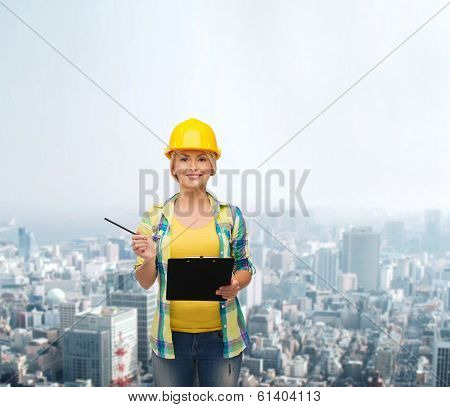 repair, construction and maintenance concept - smiling woman in helmet with clipboard