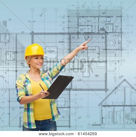 repair, construction and maintenance concept - smiling woman in helmet with clipboard pointing finger