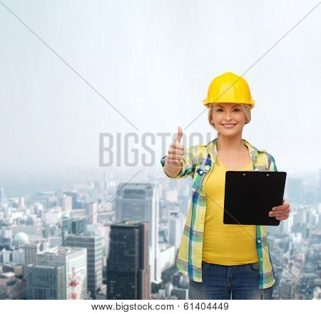 repair, construction and maintenance concept - smiling woman in helmet with clipboard showing thumbs up