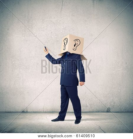 Businessman using mobile phone wearing carton box on head