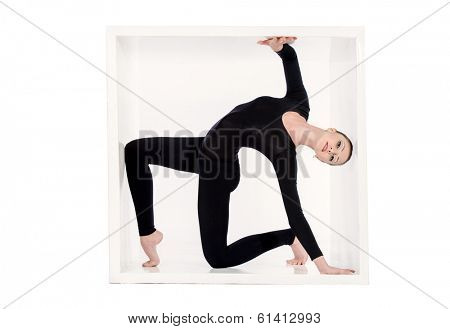 Modern bellet dancer posing with a cube at studio. Plastic body concept. Isolated over white.