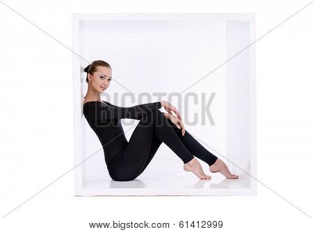 Modern bellet dancer posing with a cube at studio. Plastic body concept. Isolated over white.