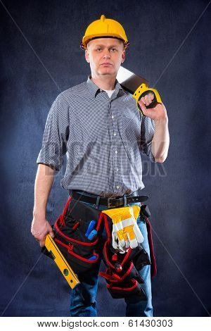 Construction worker holding a spirit level and saw