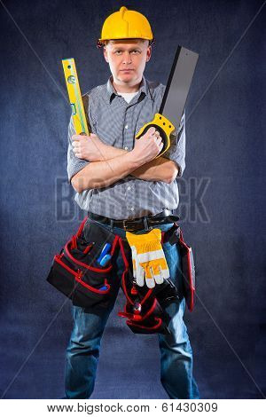 Construction worker holding a spirit level and saw