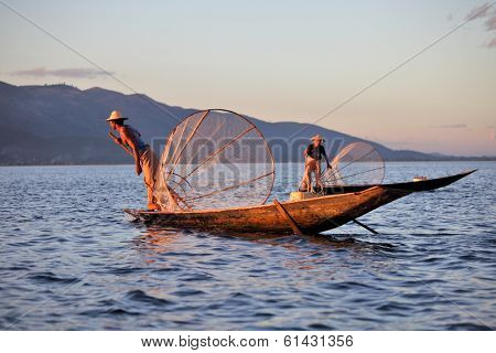 INLE LAKE, MYANMAR DECEMBER 12, 2013: Fishermen at Inle Lake, Shan State, Myanmar Intha people possess the leg-rowing style and the unique coop-like fishing equipment 