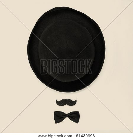 a bowler hat, a mustache and a bowtie on a beige background depicting a gentleman or a hipster guy, with a retro effect