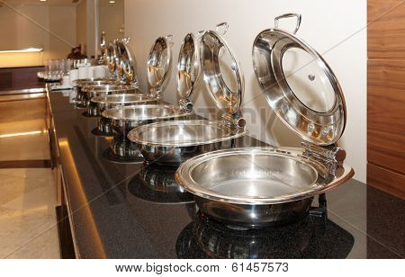 Table with shiny marmites in restaurant
