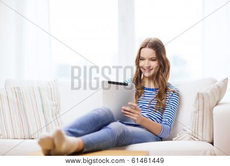 home, technology and internet concept - smiling teenge girl lying on the couch with tablet pc computer at home
