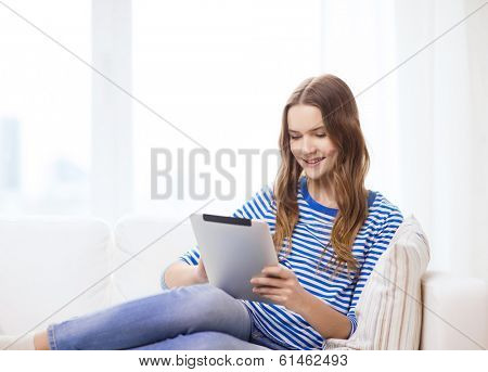 home, technology and internet concept - smiling teenge girl lying on the couch with tablet pc computer at home