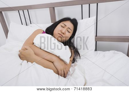 Young woman suffering from stomach ache lying in bed