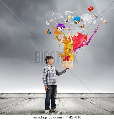 Young boy splashing colorful paint from bucket