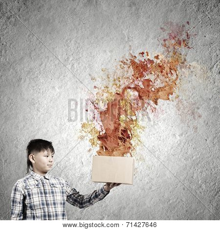 Young boy splashing colorful paint from carton box